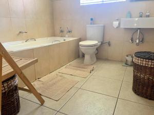 e bagno con vasca, servizi igienici e lavandino. di Happy Living Guesthouse a Vereeniging