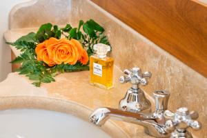 a bathroom sink with a bottle of soap and a flower at Il San Corrado di Noto in Noto