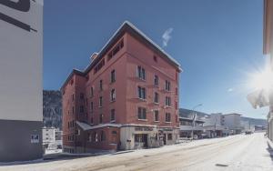 a large red brick building on a snowy street at Hotel Ochsen by Mountain Hotels in Davos