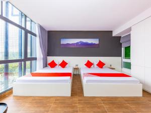 two beds in a room with red pillows at QA Hotel Dalat - City Centre in Da Lat