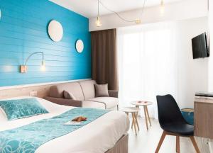 een hotelkamer met een bed en een blauwe muur bij Hôtel La Côte Océane in Saint-Jean-de-Monts