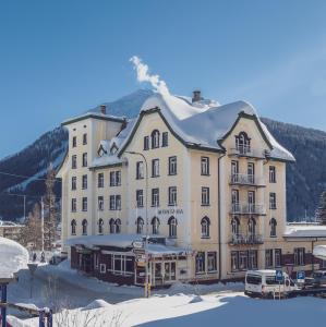 a large building with a snow covered mountain in the background at Hotel Montana by Mountain Hotels in Davos