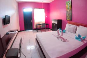 een slaapkamer met een groot bed met roze muren bij Hotel FX72 Ruteng in Ruteng
