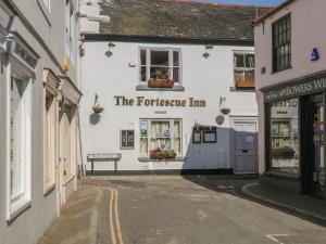 a white building with a sign that reads the tortoise inn at 33 Island Street in Salcombe