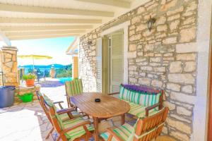 a patio with a wooden table and chairs and a stone wall at Villa Kefalaki in Katávolos