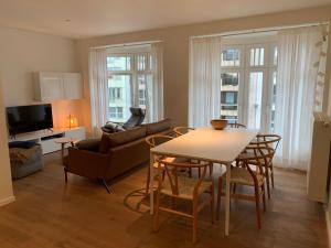 een woonkamer met een tafel en stoelen en een bank bij Appartement Delmare in De Panne