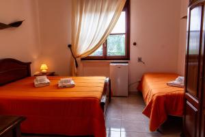 two beds in a room with a window at La Masseria Hotel Ristorante Centro Benessere in Cocumola