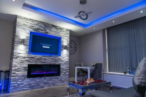 a living room with a fireplace and a tv at Aphrodite Suites Huddersfield in Huddersfield