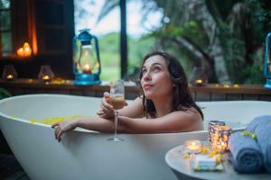 una mujer sentada en una bañera sosteniendo una copa de vino en Makakatana Bay Lodge en St Lucia