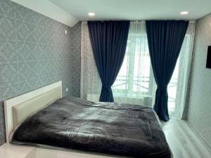 Villa Baghdo Bakuriani في باكورياني: غرفة نوم بسرير كبير مع ستائر زرقاء