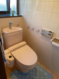a bathroom with a white toilet and a blue rug at 古民家ゲストハウス穏 in Sakaide