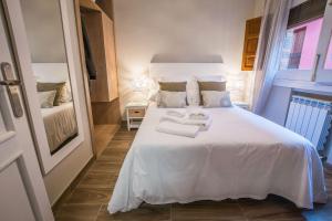 a bedroom with a white bed with towels on it at Ibericabeds Plaza Nueva Suite 21 in Granada