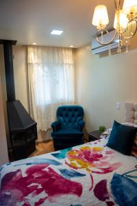 a bedroom with a bed and a blue chair at Hotel Pousada do Conde in Canela