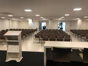 an empty lecture hall with tables and chairs at Flat Park Veredas com Vista Serra com geladeira e fogão in Rio Quente +16 photos