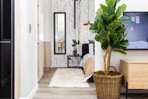 a room with a potted plant and a bedroom at Menlyn Marble Print Apartment in Pretoria