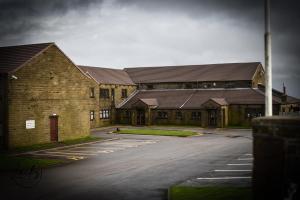 een lege parkeerplaats voor een bakstenen gebouw bij Pennine Manor Hotel in Huddersfield