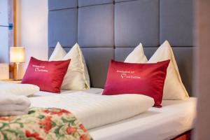 two beds with red and white pillows on them at Vötter's Hotel in Kaprun