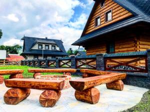 a group of wooden benches in front of a house at Wellness drevenica Hájenka Zázrivá in Zázrivá