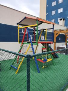 a playground with a play structure on top of a fence at Apto de Praia Fiji 1102 in Piçarras +34 photos