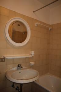 a bathroom with a sink and a tub and a mirror at Villaggio Santa Lucia in Ledro