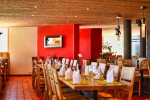 un restaurante con mesas y sillas de madera y una pared roja en Hotel Jungfrau en Fiesch
