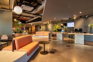 a lobby with orange chairs and a counter in a building at Novotel Criciuma in Criciúma