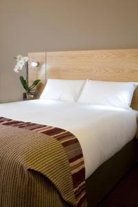 a bedroom with a large bed with a wooden headboard at Jurys Inn Aberdeen in Aberdeen