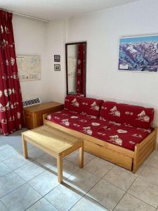 ein Wohnzimmer mit einem roten Sofa und einem Tisch in der Unterkunft Boost Your Immo Prapelier Les Deux Alpes 430 in Les Deux Alpes