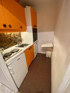 eine kleine Küche mit orangefarbenen Schränken und einem Waschbecken in der Unterkunft Boost Your Immo Prapelier Les Deux Alpes 430 in Les Deux Alpes
