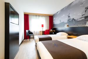 ザーンダムにあるバスティオン ホテル ザーンダムのベッド3台と大きな壁画が備わるホテルルームです。