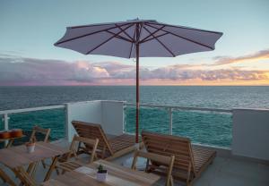 uma varanda com cadeiras e um guarda-sol no oceano em La Plage Salvador - Boutique Hostel em Salvador