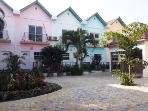 a row of pink and white buildings with plants at Riyan Apartment in Kololi