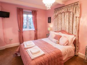 a pink bedroom with a bed with two towels on it at Yardley Manor in Scarborough