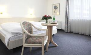 a bedroom with a table and a bed and a chair at Landhaus Michels garni in Kaarst