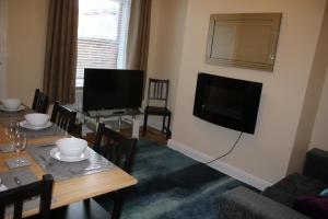 a living room with a table and a flat screen tv at Carvetii - Quentin House - Near Hospital, max 7 ppl in Carlisle