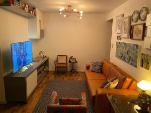 sala de estar con sofá y TV de pantalla plana en Apto continente Florianópolis, en Florianópolis