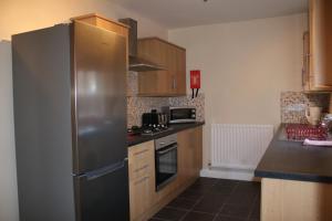 a kitchen with a stainless steel refrigerator and wooden cabinets at Carvetii - Quentin House - Near Hospital, max 7 ppl in Carlisle