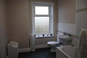 a bathroom with a toilet and a sink and a window at Carvetii - Quentin House - Near Hospital, max 7 ppl in Carlisle