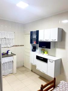 eine Küche mit weißen Schränken und einer Arbeitsplatte in der Unterkunft Peruibe centro mar 944 in Peruíbe + 10 Fotos