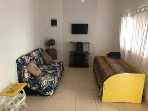 a living room with a couch and a tv at Peruibe centro mar 944 in Peruíbe