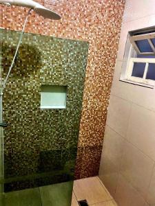 eine Dusche mit Glastür und Ziegelwand in der Unterkunft Peruibe centro mar 944 in Peruíbe
