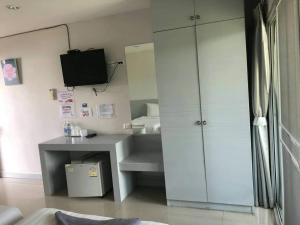 a room with a desk and a cabinet with a television at Rose Villa Hote in Pak Chong