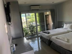 a hotel room with two beds and a balcony at Rose Villa Hote in Pak Chong