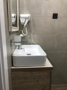 uma casa de banho com um lavatório branco e um secador de cabelo em Milmari apartman SAN-28 em Kopaonik