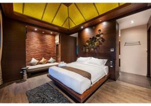 a bedroom with a large white bed and a couch at Nirvana Beach Resort, Koh Lanta SHA Extra Plus in Ko Lanta