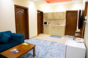 a living room with a blue couch and a kitchen at بــــاســــيل للشقق المخدومة in Hafr Al-Batin