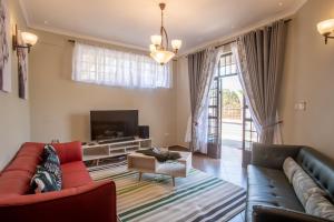 a living room with a couch and a tv at Kinga Homes Boutique Hotel in Moshi