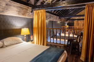 a bedroom with a bed with yellow curtains and a table at The Clock Hostel & Suites in Cartagena de Indias