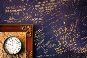 a clock on a wall with writing on it at The Clock Hostel & Suites in Cartagena de Indias