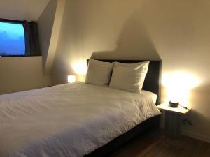 - une chambre avec un lit doté de draps blancs et une fenêtre dans l'établissement De Groene Leeuw & De Zeven Provinciën, à Flessingue